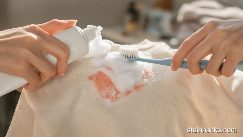 手挤剃须膏在衣物污渍上并用软刷画圈清洗的微距镜头